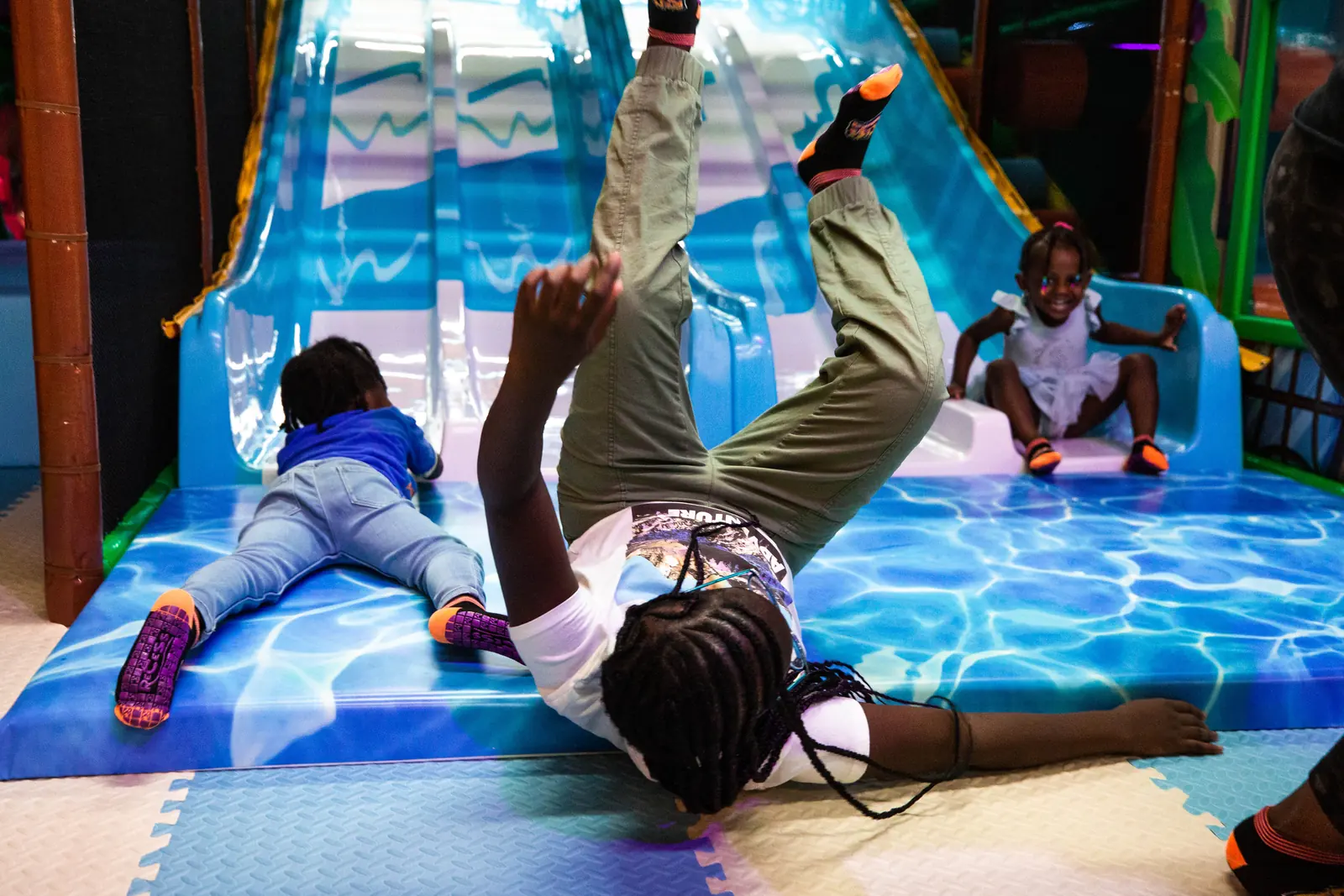 A child sliding down the tall indoor slide mid-ride