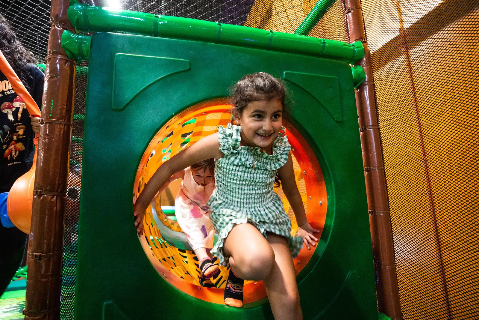 A child crawling through a padded tunnel in the play structure