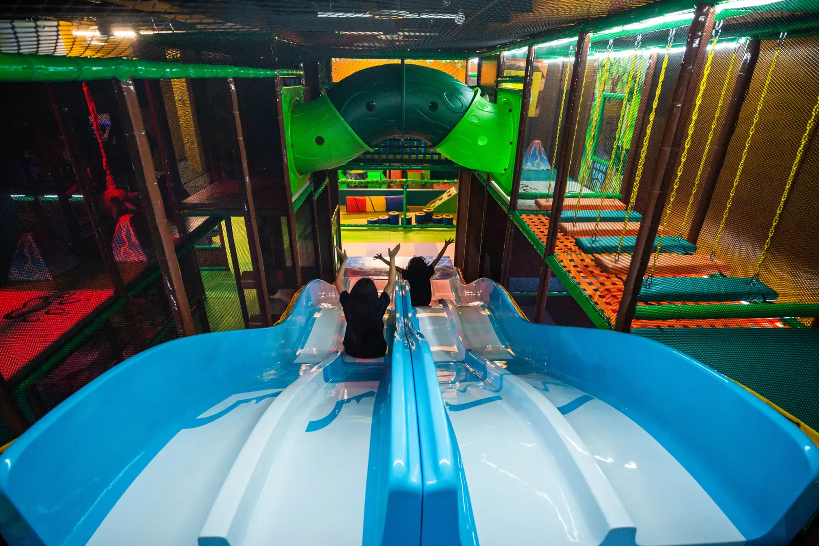 Two children at the top of the double slide getting ready to go