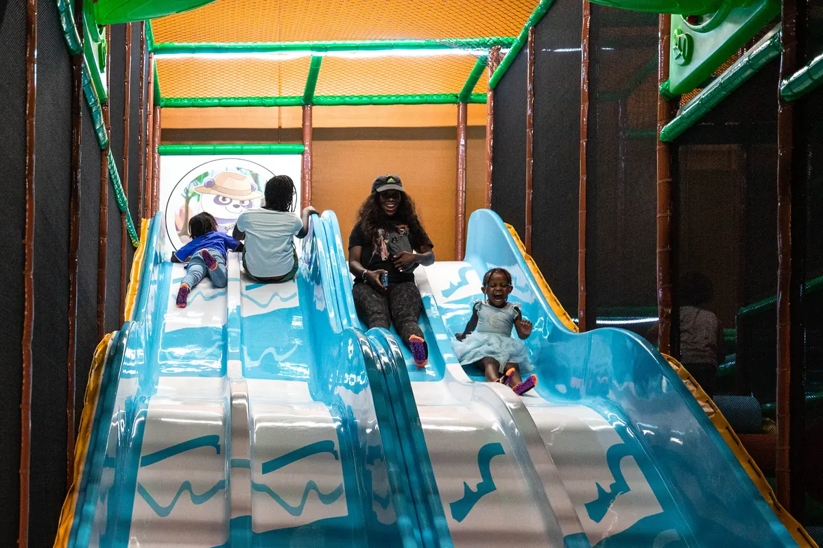 A child at the top of the tall indoor slide