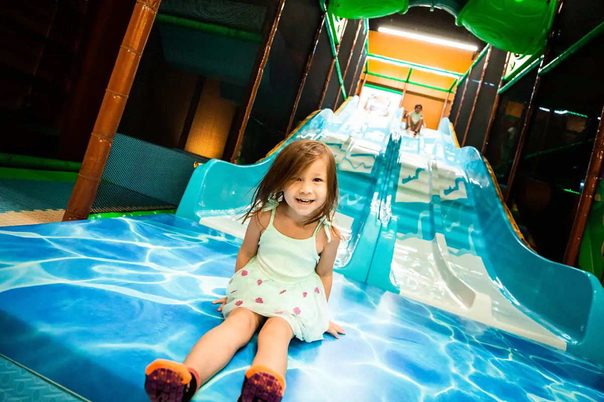 A toddler coming down a small beginner slide