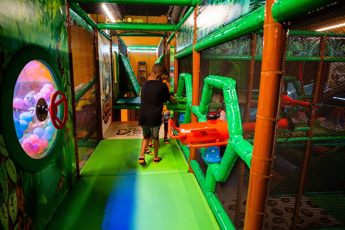 A child crawling through a padded tunnel in the play structure