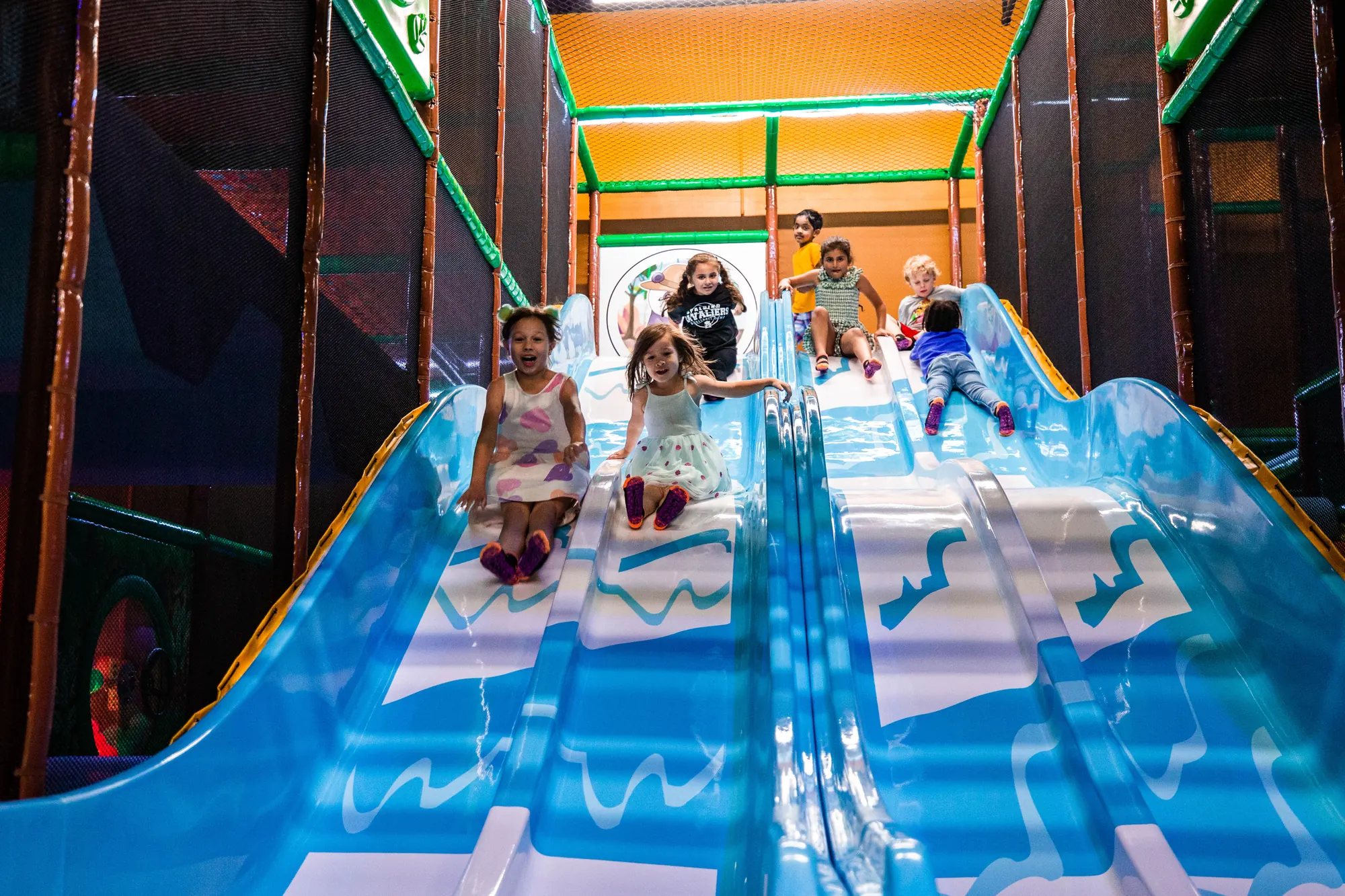 Children racing down the wide indoor slides at Recess Play Centers