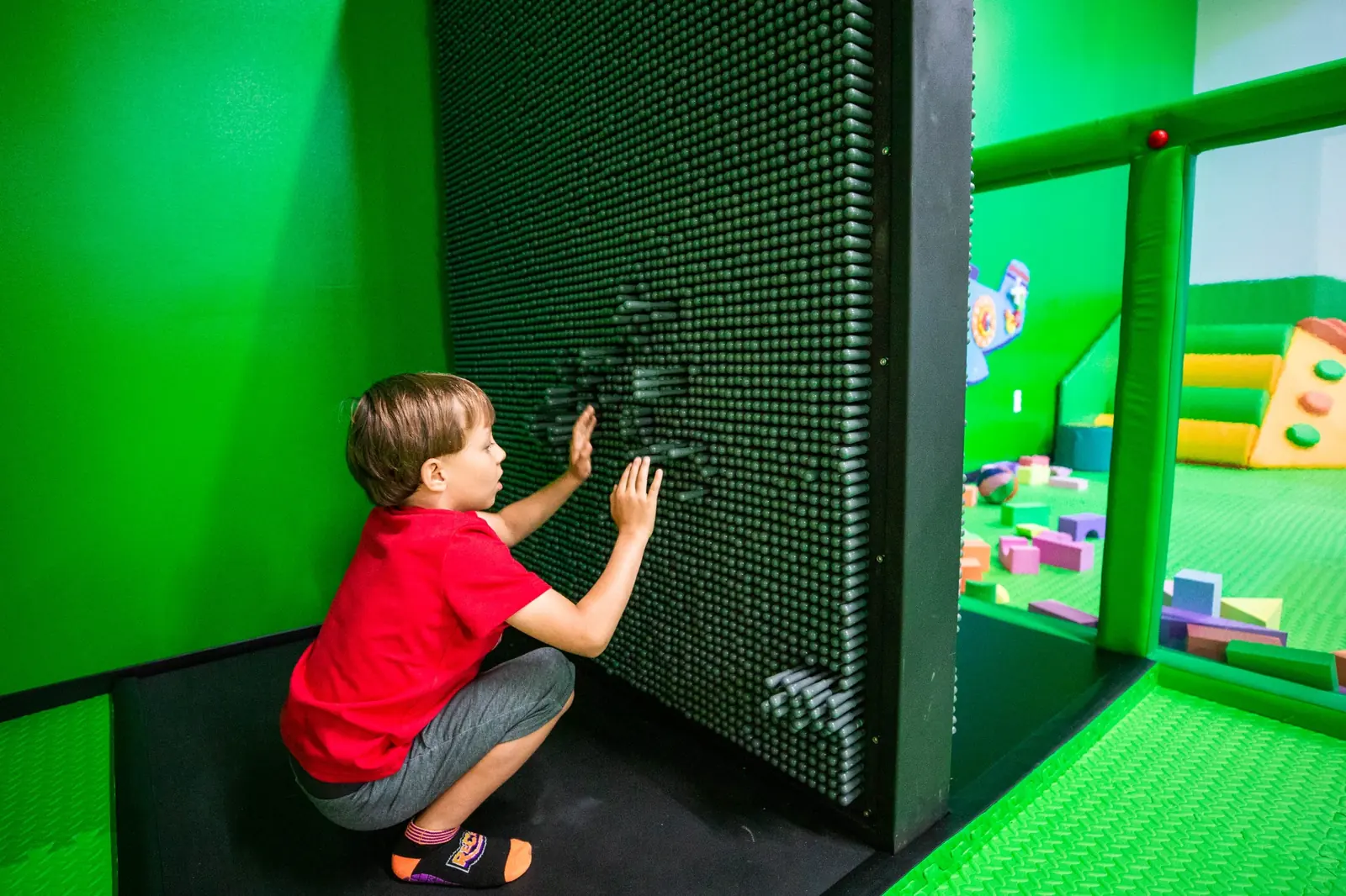 A child making an impression on the large pin-art play wall